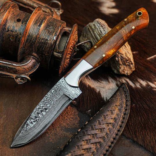 A fixed-blade knife with a patterned Damascus steel blade and a polished amber-brown wood handle, displayed diagonally on a rustic background with a matching leather sheath.