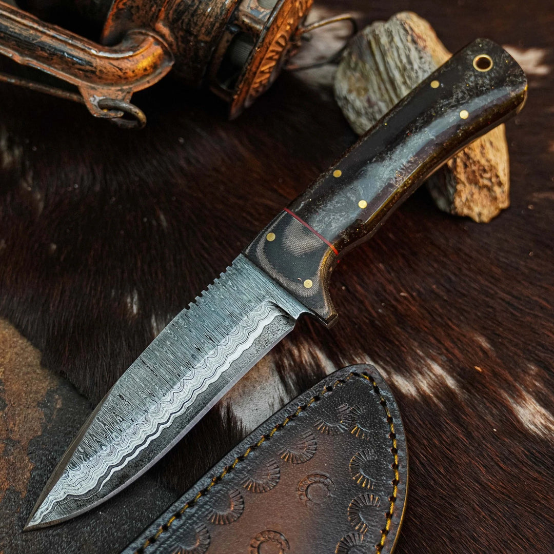 A fixed-blade knife with a patterned steel blade and a dark wood handle with brass pins, shown resting on a brown fur surface with a leather sheath and rustic outdoor props.