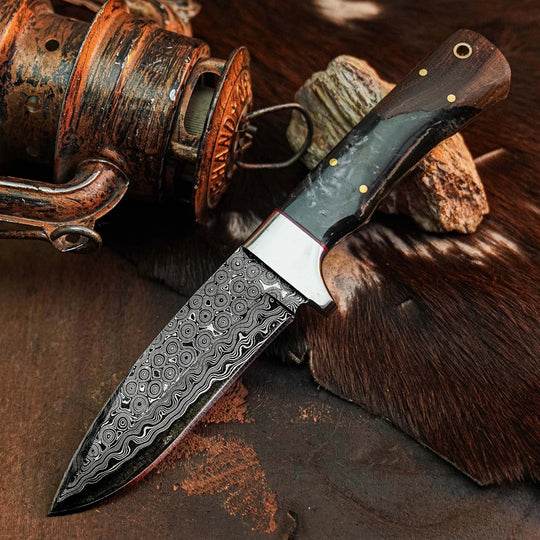 A custom Damascus steel fixed-blade knife with a patterned blade and a dark wood handle, styled on a rustic background with a vintage lantern and brown fur.