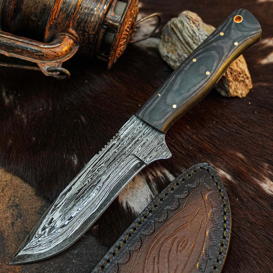 A fixed-blade knife with a patterned Damascus-style steel blade, a dark wood handle with brass pins, and a brown leather sheath, arranged on a dark fur surface with rustic props.